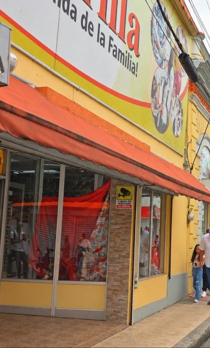 Fachada de Tienda Amarilla en Moca, con toldo naranja y letrero